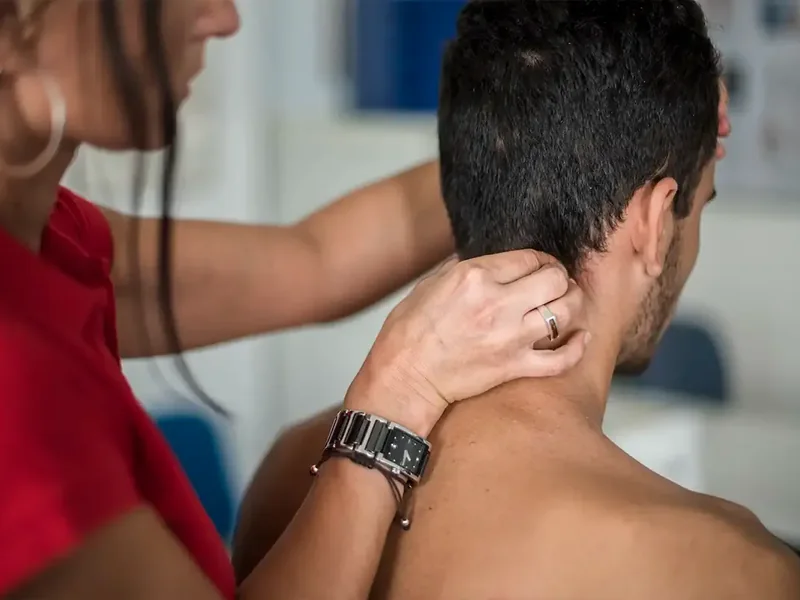A licensed physical therapist checking neck rotation during a cause-first evaluation in Reseda
